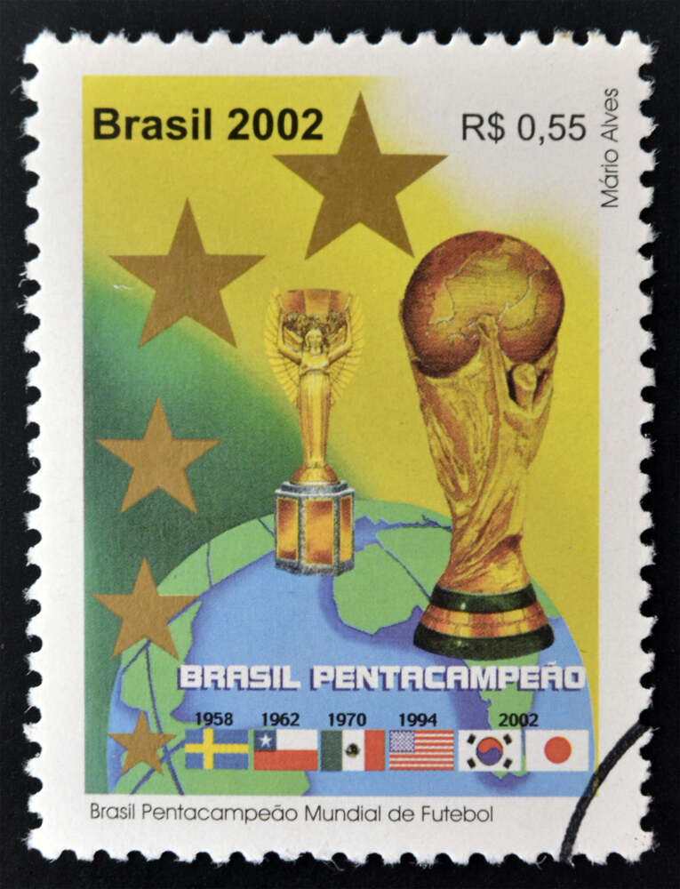Selo postal brasileiro comemorativo do Pentacampeonato Mundial de 2002. A arte exibe os dois troféus da Copa do Mundo (Jules Rimet e a Taça atual), as cinco estrelas e os anos das conquistas (1958, 1962, 1970, 1994 e 2002), celebrando um capítulo essencial n'a história do futebol.