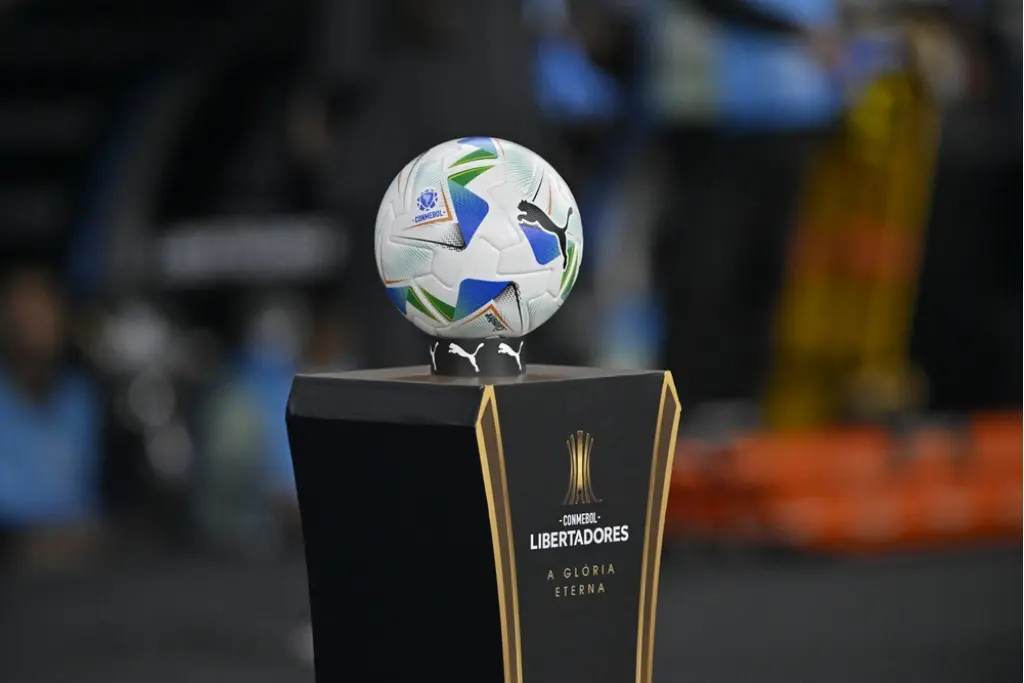 Fotografia em close da bola oficial da Conmebol sobre um totem preto com a inscrição A Glória Eterna, representando o prestígio alcançado pelos clubes com mais finais de Libertadores disputadas na história do futebol sul-americano.