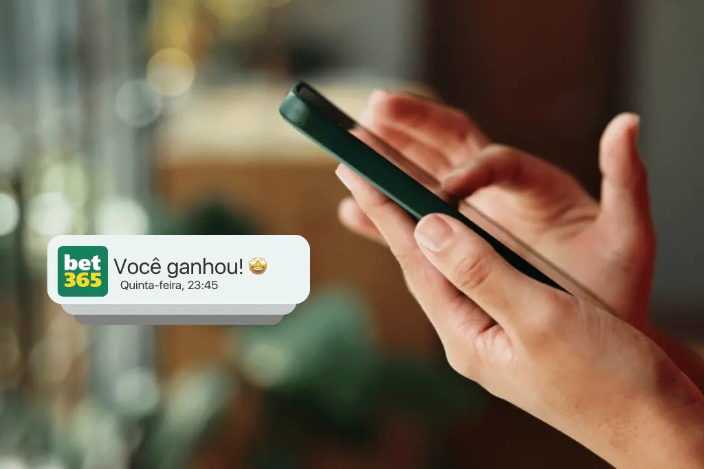 Close das mãos de uma pessoa segurando um smartphone com uma notificação de vitória da Bet365 em destaque. A imagem ilustra o uso das melhores bets em dispositivos móveis, com fundo desfocado.