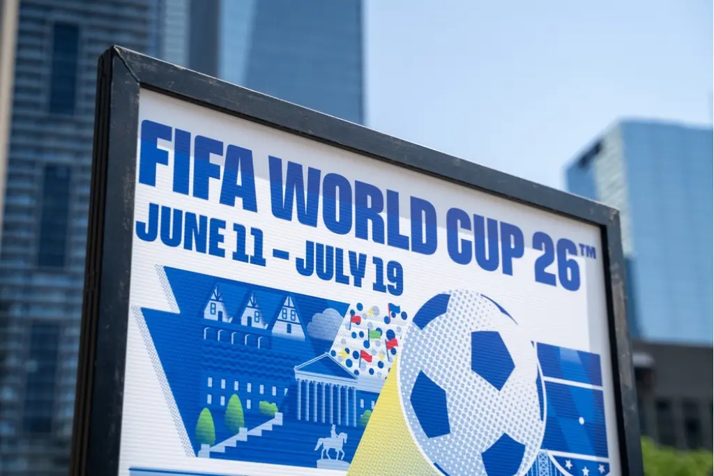 Placa informativa de rua com a identidade visual da FIFA World Cup 26, exibindo as datas 11 de junho a 19 de julho. O cartaz simboliza a organização do torneio onde jogará o grupo do Brasil na Copa do Mundo de 2026 na América do Norte.