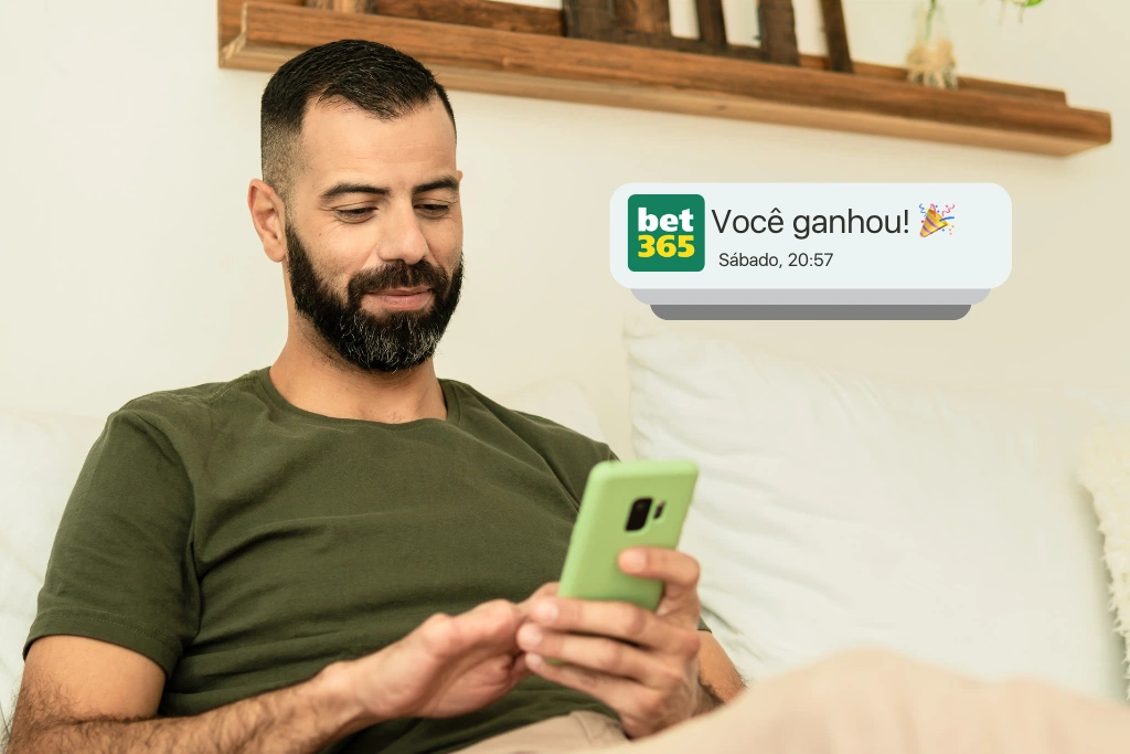 Homem de camiseta verde sorri ao olhar para o celular, recebendo uma notificação fictícia da Bet365 com a mensagem "Você ganhou!". Uma imagem que ilustra o resultado positivo de uma aposta para Copa do Mundo.
