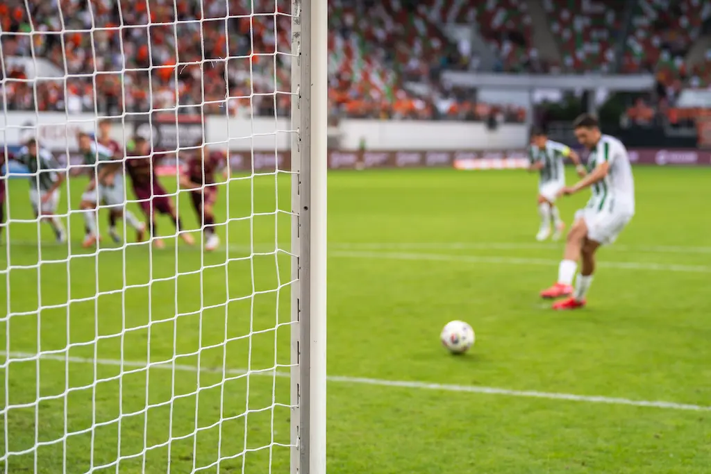 Detalhe do post do gol com rede e jogador de futebol durante o pênalti no fundo