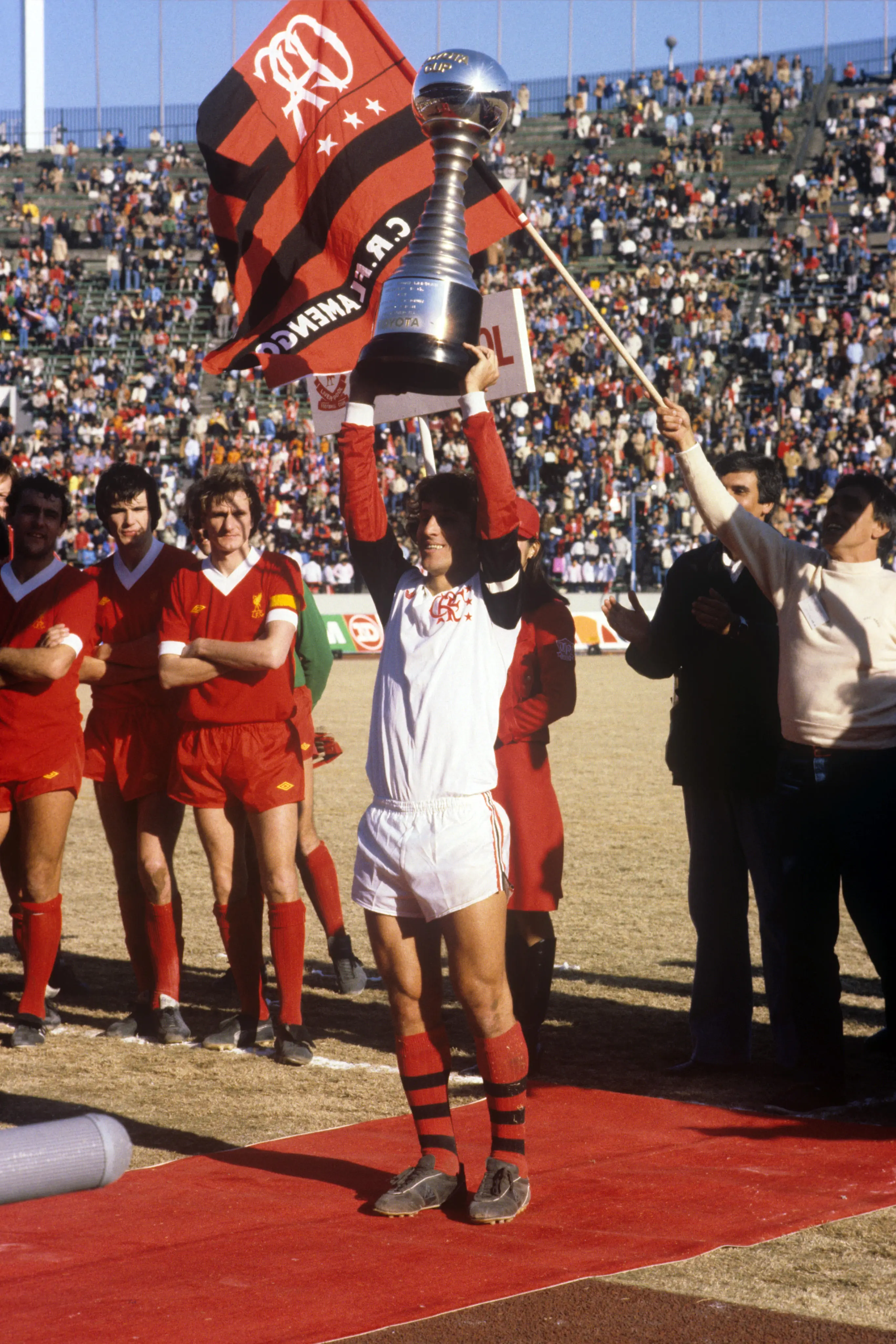 O capitão do Flamengo, Zico, exibe a Taça de Tóquio enquanto Ray Kennedy, Alan Hansen e Phil Thompson, do Liverpool (da esquerda para a direita), observam.